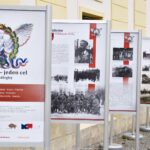 Ilustracja przedstawia szereg tablic wystawowych ustawionych na tle ratusza w Bielsku Podlaskim.