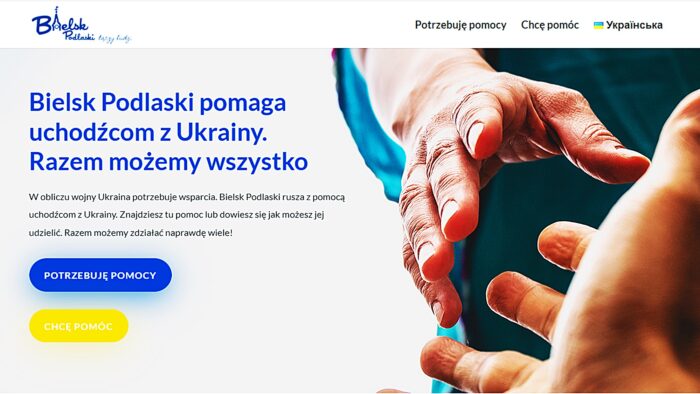 Ilustracja przedstawia fragment strony startowej serwisu BielskPomaga.pl. Widać na niej wyciągnięte ku sobie dłonie, a także napis: "Bielsk Podlaski pomaga uchodźcom z Ukrainy. Razem możemy wszystko".