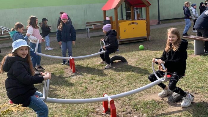 Dzieci bawiące się na przyszkolnym placu zabaw.
