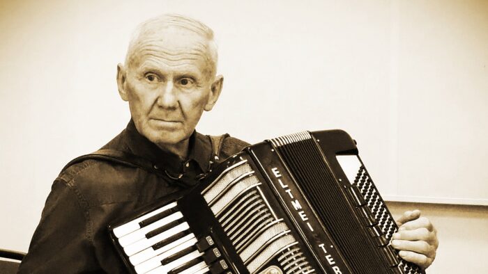 Czarno-białe zdjęcie Mikołaja Turkowicza grającego na akordeonie.