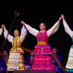 Kolorowo ubrani tancerze i tancerki na scenie Bielskiego Domu Kultury podczas festiwalu "Podlaskie spotkania 2022".