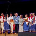Kolorowo ubrani tancerze i tancerki na scenie Bielskiego Domu Kultury podczas festiwalu "Podlaskie spotkania 2022".