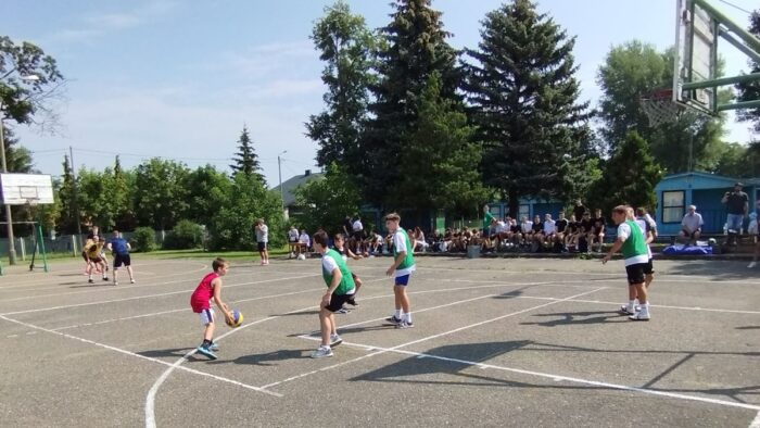 Dziesięciu chłopców gra w koszykówkę na asfaltowym boisku do streetballa. Są podzieleni na zespoły i grają dwa mecze. W tle kilkudziesięciu młodych ludzi siedzi na trybunach, obserwuje ich zmagania i czeka na swój występ.