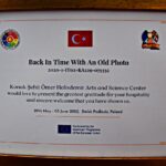 Pamiętkowy dyplom z tekstem w języku tureckim, oprawiony w złotą ramkę.