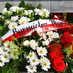 Wieniec kwiatów w barwach bieli i czerwieni z wieńcem z napisem Burmistrz Miasta Bielsk Podlaski