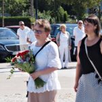 Delegacja domu kultury: dfwie kobiety niosące wiązankę kwiatów