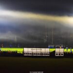 Boisko piłkarskie ze sztuczną nawierzchnią nocą. Obiekt oświetlają reflektory oświetlenia obiektu. Widoczna mgła snująca się nad boiskiem.