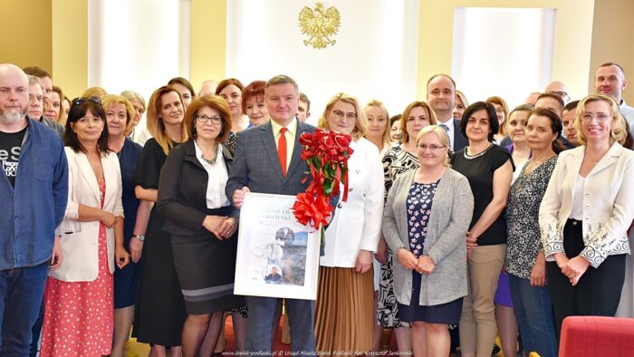 Zdjęcie grupowe kilkudziesięciu osób - pracowników urzędu miasta. Grupowo pozują do zdjęcia wokół stojącego na środku burmistrza.
