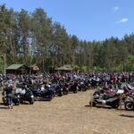 Dużo motocykli zaparkowanych na polanie leśnej. W tle drzewa.