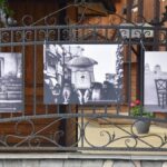 Reprodukcje fotografii wiszące na płocie przed cerkwią.