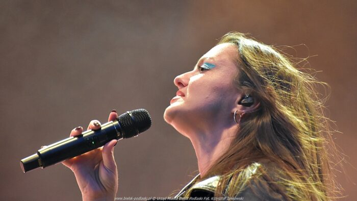 Piosenkarka na scenie śpiewająca do mikrofonu.