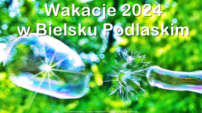 Wielka bombka mydlana na tle zieleni parkowej. Na górze napis "Wakacje 2024 w Bielsku Podlaskim".