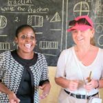 Zdjęcie dwóch kobiet z Kenii i z Bielska Podlaskiego na tle szkolnej tablicy.