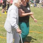 starsza kobieta o lasce i prowadzona pod rękę podczas pokonywania trasy zawodów.