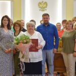 Zdjęcie z uroczystości pożegnania pracownicy w gronie koleżanek i kolegów z urzędu miasta.