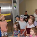 Burmistrz rozmawia z grupą dzieci na korytarzu urzędu. W tle - winda.