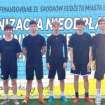 Młodzi ludzie w strojach sportowych stoją w rzędzie i pozują do zdjęcia. W tle baner z informacją o finansowaniu zawodów przez Miasto Bielsk Podlaski.