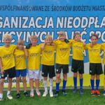 Młodzi ludzie w strojach sportowych stoją w rzędzie i pozują do zdjęcia. W tle baner z informacją o finansowaniu zawodów przez Miasto Bielsk Podlaski.