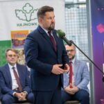 Mężczyzna wypowiada się do mikrofonu. Za nim siedzą inni uczestnicy konferencji.