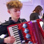 Młody mężczyzna grający na harmonii.