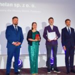 Grupa osób pozuje do grupowego zdjęcia na scenie.