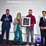 Grupa osób pozuje do grupowego zdjęcia na scenie.