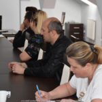 Kilka osób siedzących przy długim stole.