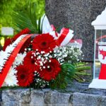 Kwiaty i znicz przed pomnikiem.