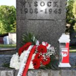 Kwiaty i znicz przed pomnikiem.