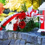 Kwiaty i znicz przed pomnikiem.
