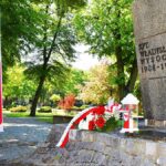 Kwiaty i znicz przed pomnikiem.