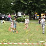 Festyn plenerowy w parku i bawiące się dzieci.