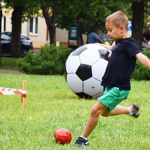 Festyn plenerowy w parku i bawiące się dzieci.