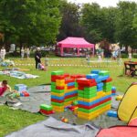 Festyn plenerowy w parku i bawiące się dzieci.