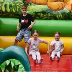 Jarmark Jagielloński w parku: stragany i zabawy dzieci na dmuchańcach.