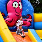 Jarmark Jagielloński w parku: stragany i zabawy dzieci na dmuchańcach.