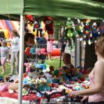 Jarmark Jagielloński w parku: stragany i zabawy dzieci na dmuchańcach.