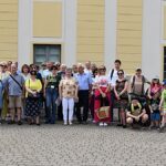 Grupa osób spacerujących po mieście z przewodniczką PTTK.