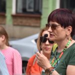 Grupa osób spacerujących po mieście z przewodniczką PTTK.