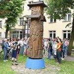 Grupa osób spacerujących po mieście z przewodniczką PTTK.