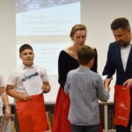 Dorośli i dzieci na turnieju wiedzy w bibliotece.