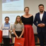 Dorośli i dzieci na turnieju wiedzy w bibliotece.