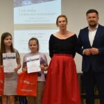 Dorośli i dzieci na turnieju wiedzy w bibliotece.