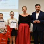 Dorośli i dzieci na turnieju wiedzy w bibliotece.