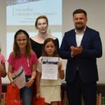 Dorośli i dzieci na turnieju wiedzy w bibliotece.