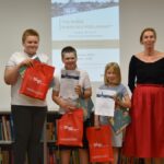 Dorośli i dzieci na turnieju wiedzy w bibliotece.