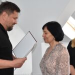 Mężczyzna i dwie kobiety podczas wręczania podziękowań i gratulacji.