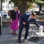 Uroczyste ustawianie płonących zniczy przed pomnikami.