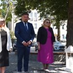 Uroczyste ustawianie płonących zniczy przed pomnikami.