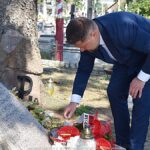 Uroczyste ustawianie płonących zniczy przed pomnikami.